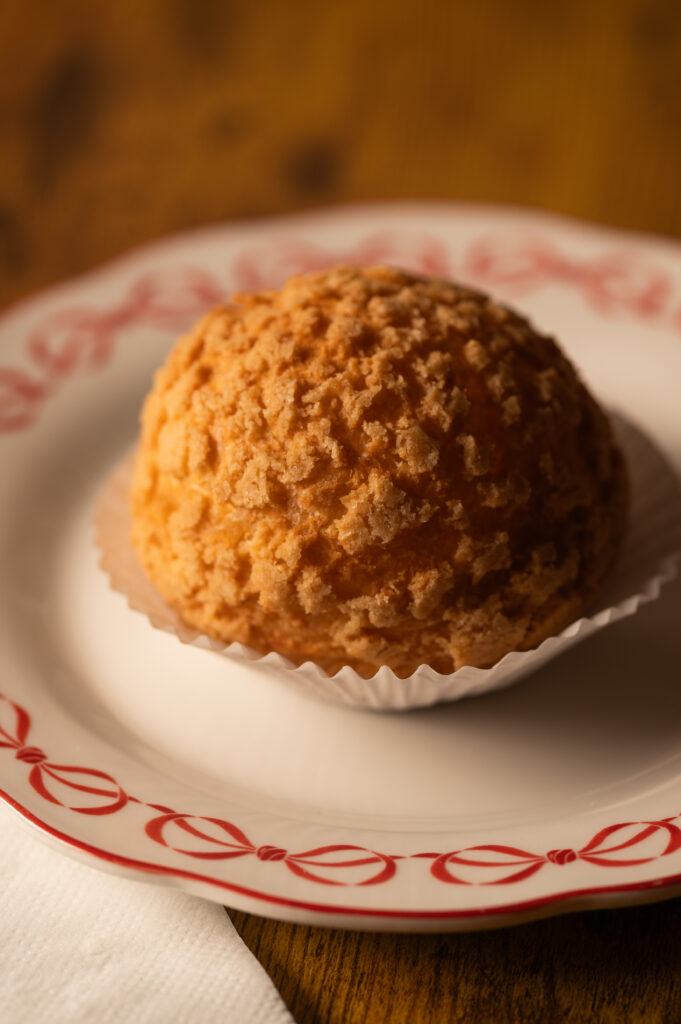 A Cookie Puff with a crisp craquelin top on a red-trimmed plate